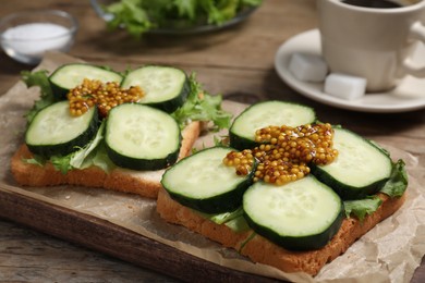 Photo of Tasty cucumber sandwiches with arugula and mustard on wooden table, closeup