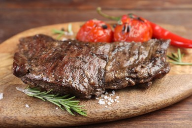 Photo of Delicious roasted beef meat, vegetables and spices on wooden table, closeup