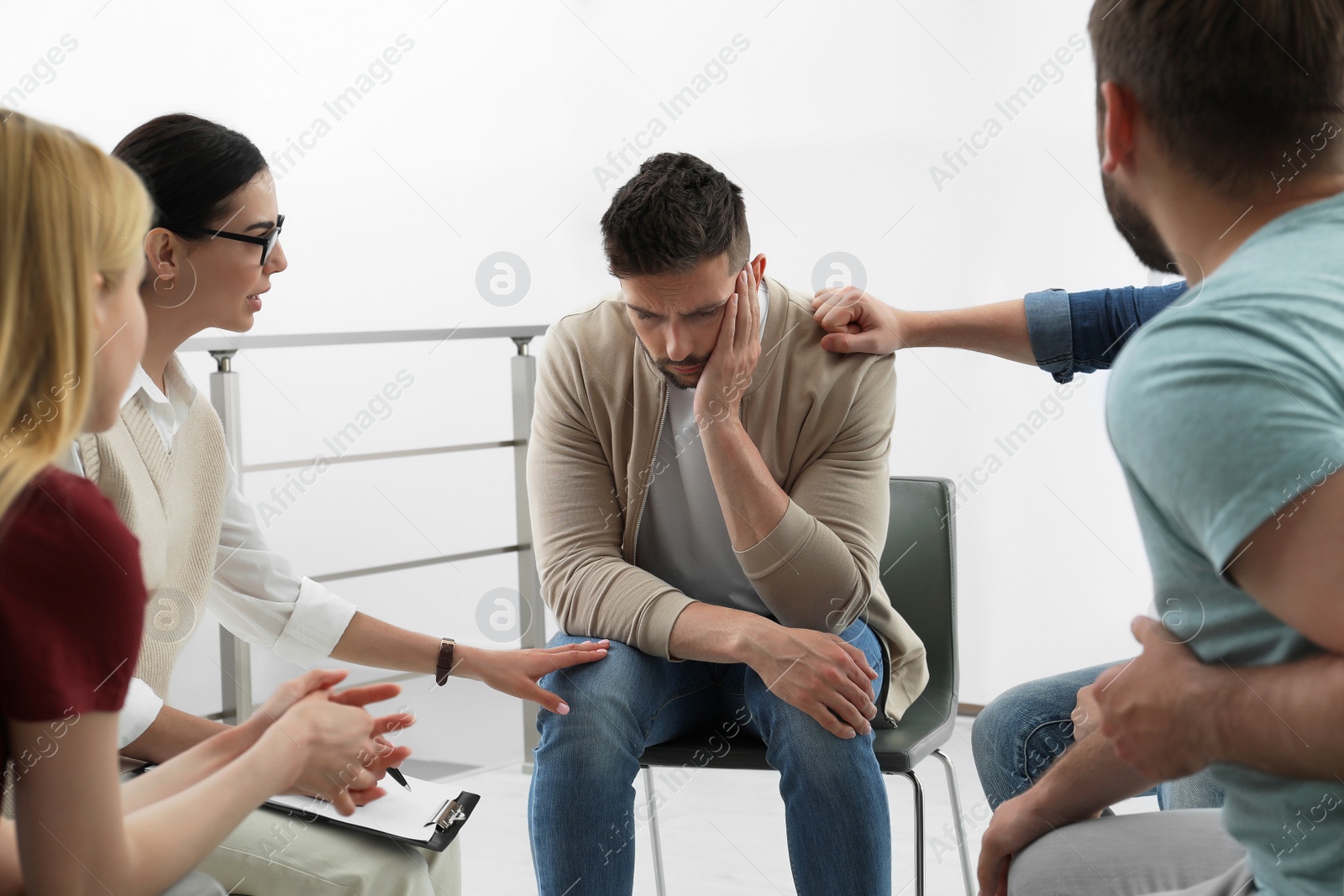 Photo of Psychotherapist working with group of drug addicted people at therapy session indoors