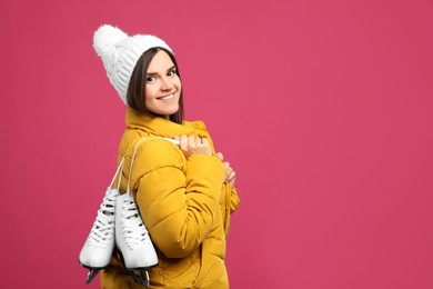 Happy woman with ice skates on pink background. Space for text
