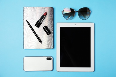 Photo of Flat lay composition with tablet, mobile phone and blogger's stuff on light blue background