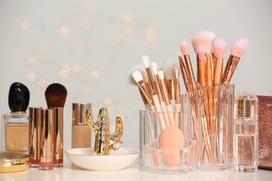 Photo of Set of cosmetic products and makeup brushes on dressing table