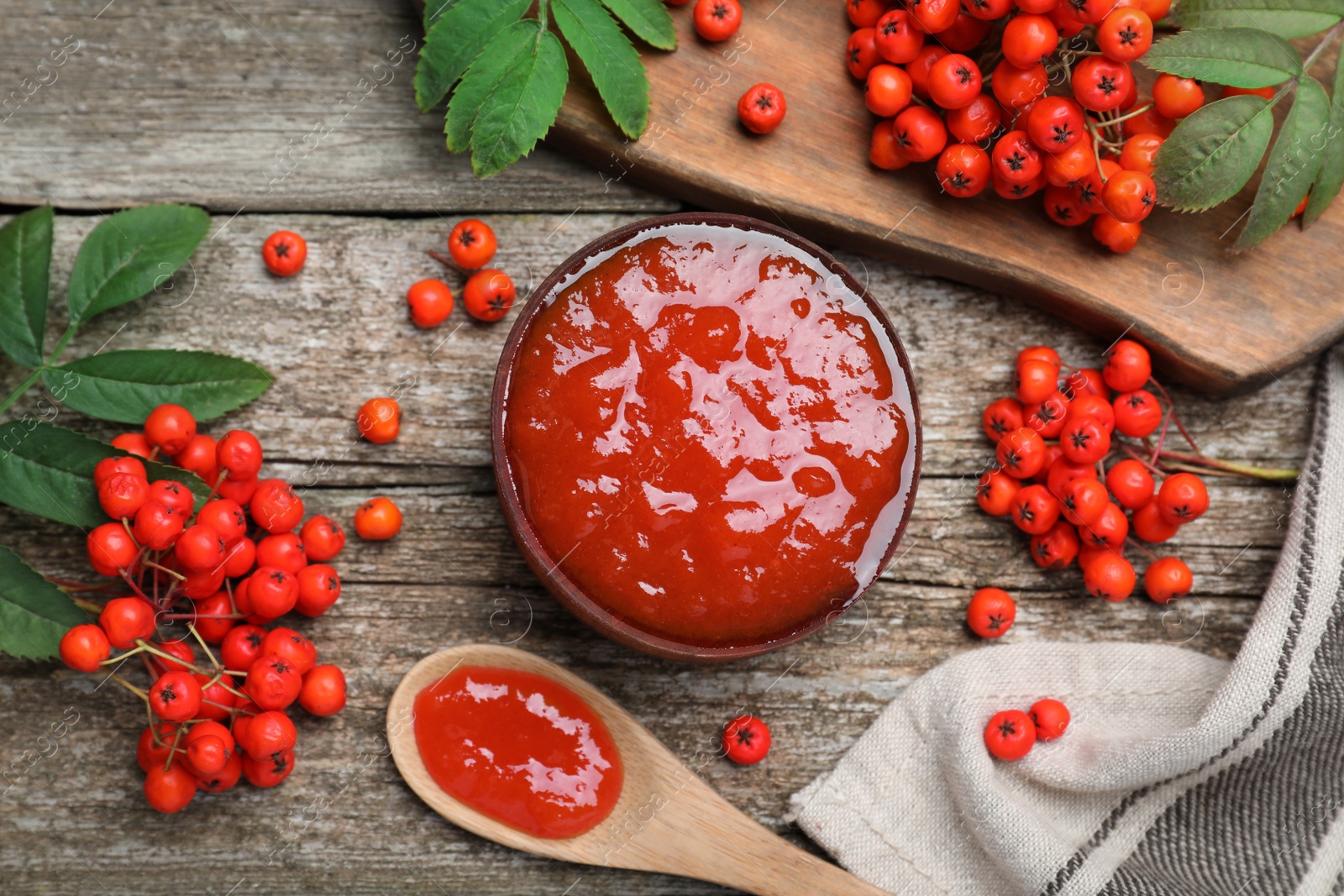 Photo of Delicious rowan jam and berries on wooden table, flat lay