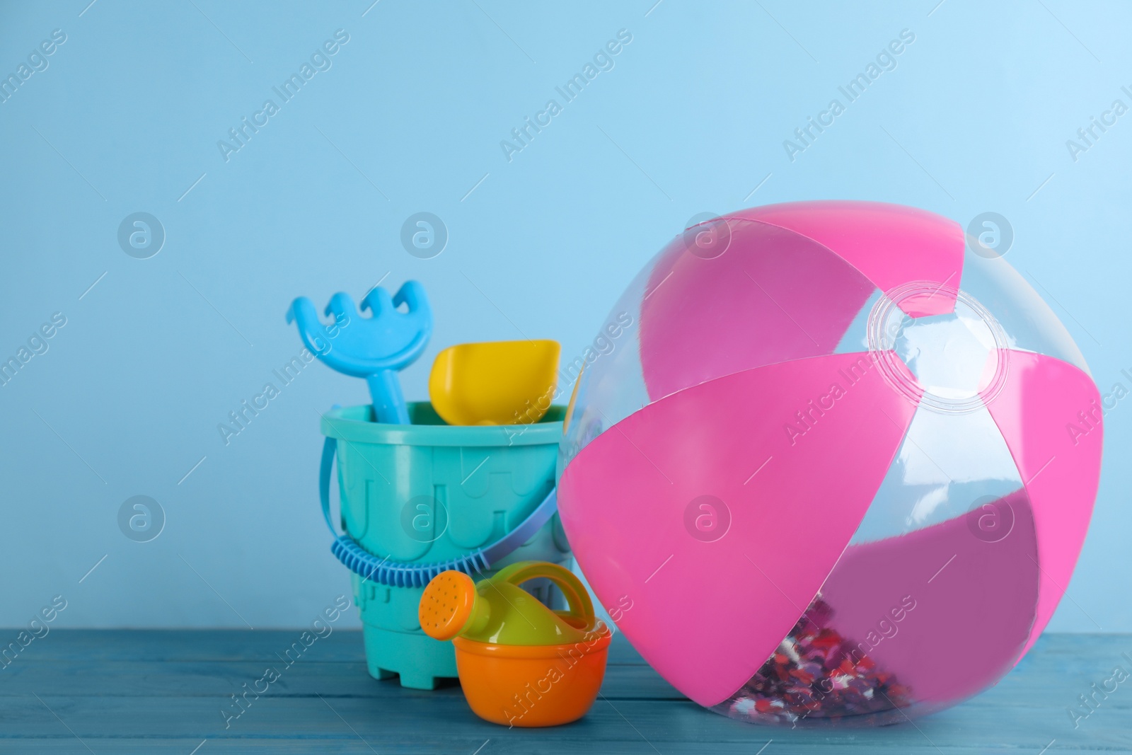 Photo of Inflatable beach ball and sand toys on light blue wooden table