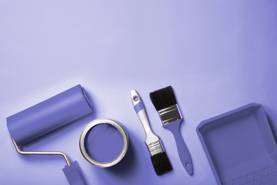 Flat lay composition with paint and decorator tools on violet background