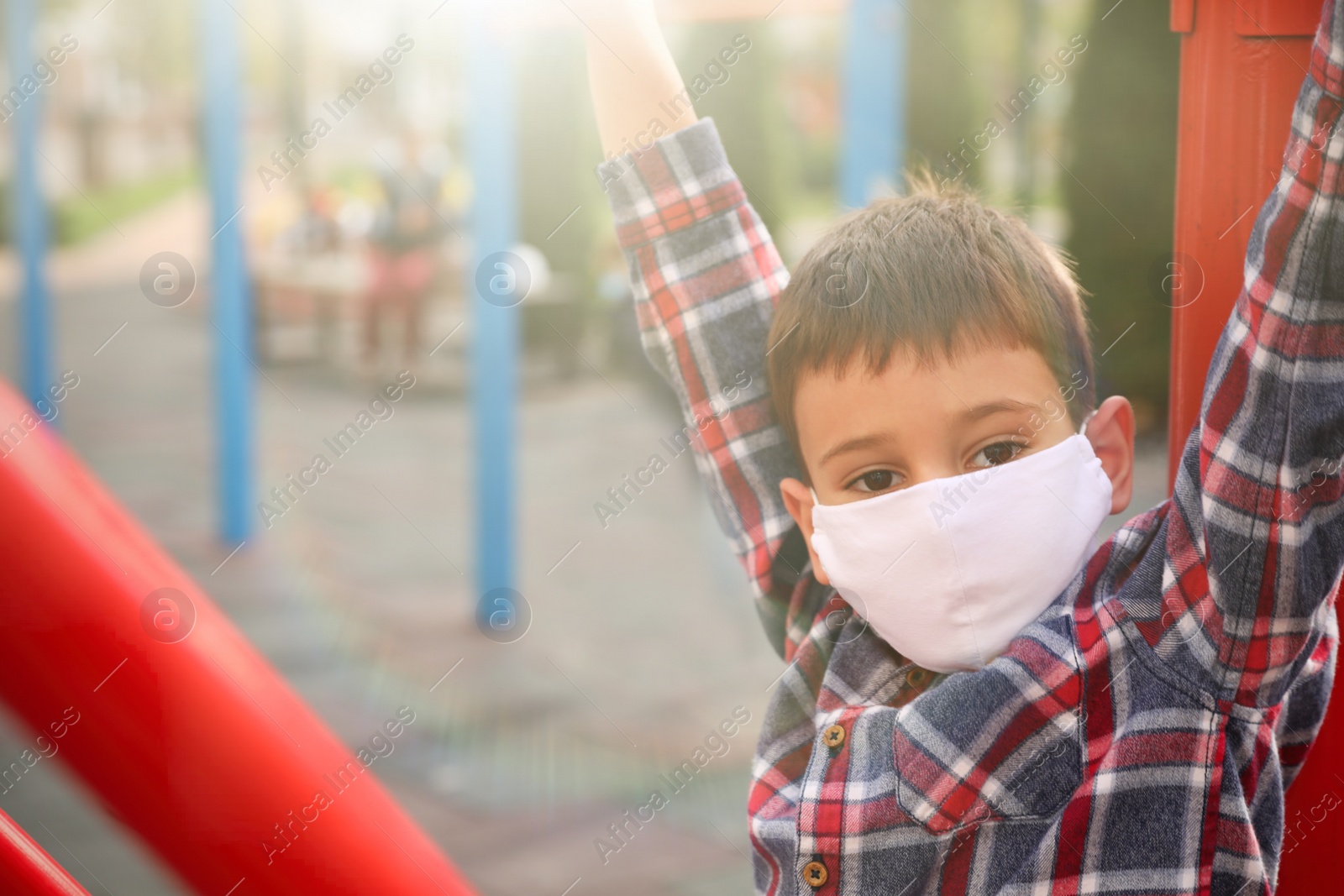 Photo of Little boy with medical face mask on playground during covid-19 quarantine