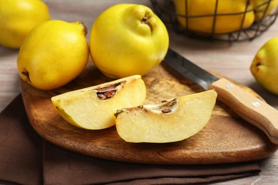 Photo of Ripe whole and cut quinces with knife on table, closeup