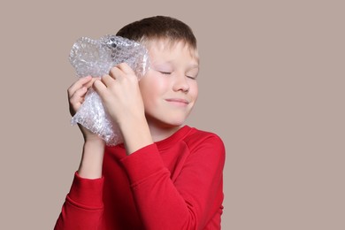 Boy popping bubble wrap on beige background. Stress relief