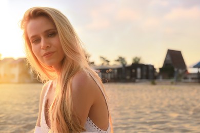 Beautiful young woman on sandy beach, space for text