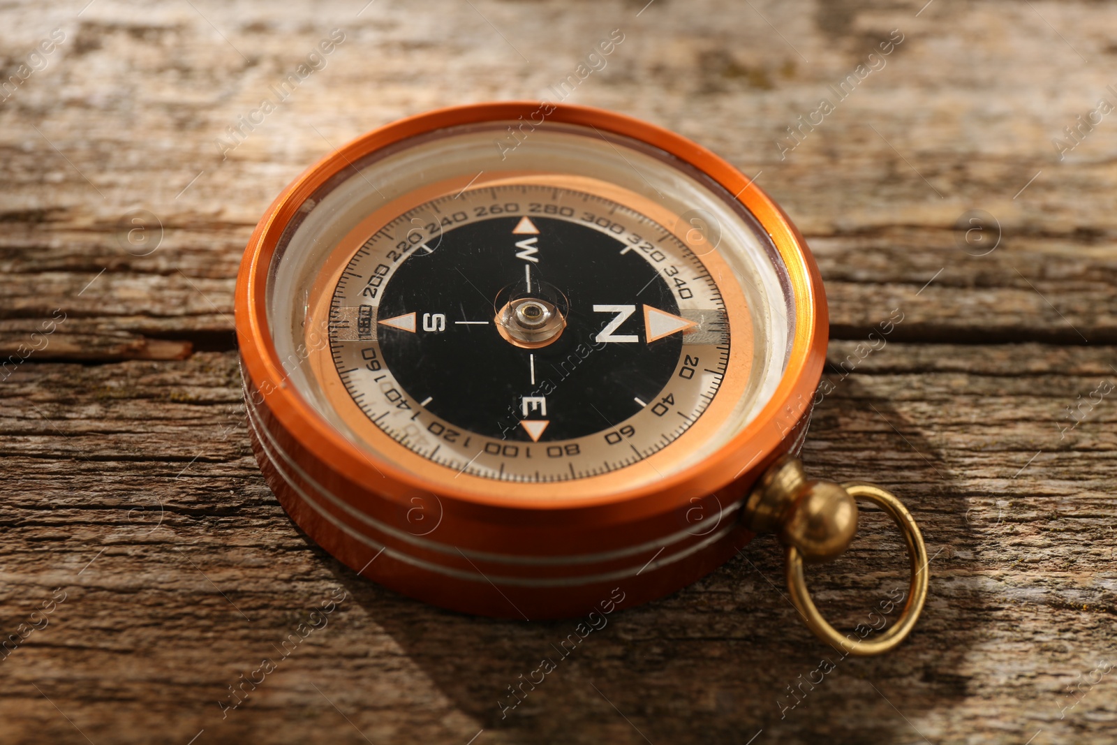 Photo of One compass on wooden table, closeup. Tourist equipment