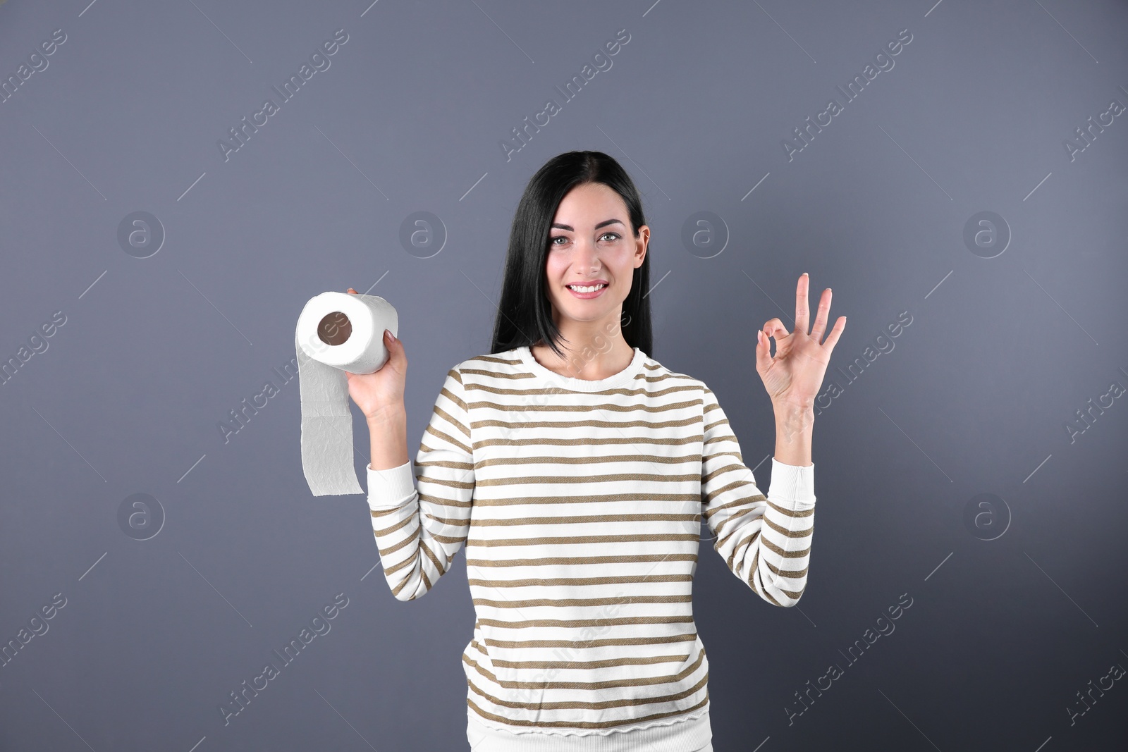 Photo of Beautiful woman holding toilet paper roll on color background