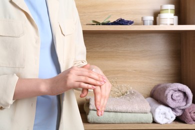 Photo of Woman applying hand cream at home, closeup