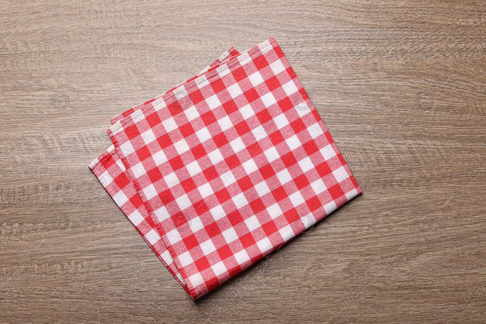 Photo of Checkered tablecloth on wooden table, top view