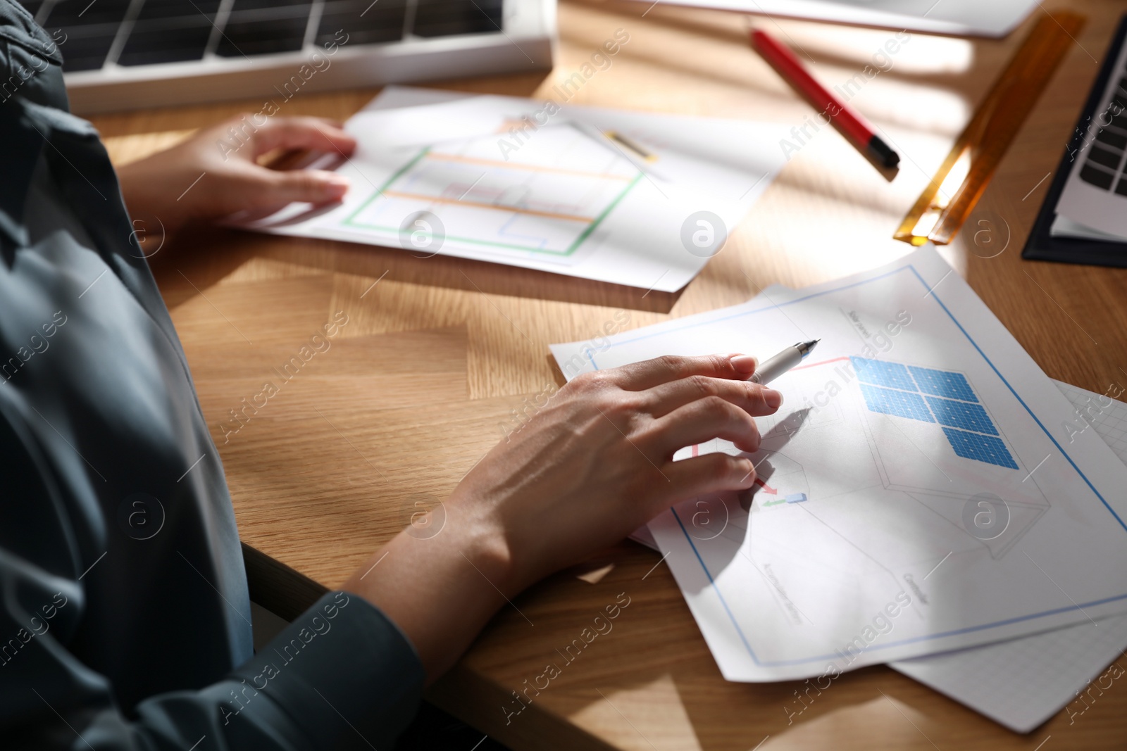 Photo of Woman working on house project with solar panels at table in office, closeup