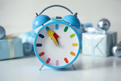 Photo of Alarm clock with Christmas decor on white table, closeup. New Year countdown