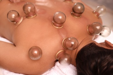 Photo of Cupping therapy. Closeup view of man with glass cups on his back in spa salon
