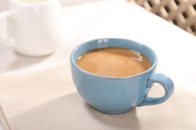 Photo of Delicious coffee in cup on white table, closeup. Space for text