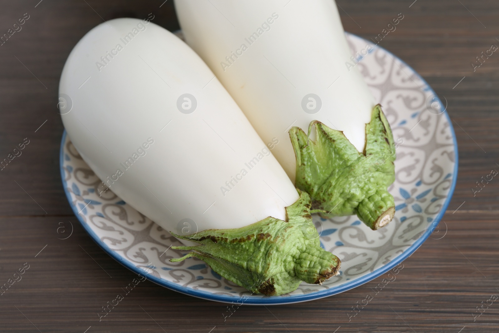 Photo of Two fresh white eggplants on wooden table, closeup