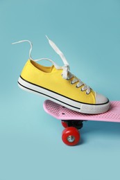 Photo of Yellow classic old school sneaker on skateboard against light blue background