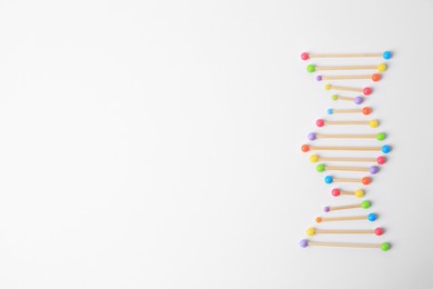 Photo of DNA molecule model made of toothpick and colorful beads on white background, flat lay. Space for text