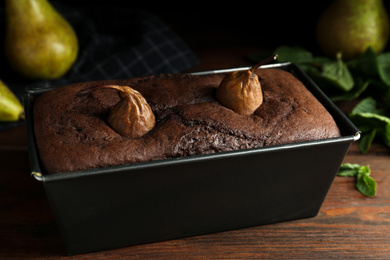 Photo of Tasty pear bread in baking form on wooden table. Homemade cake