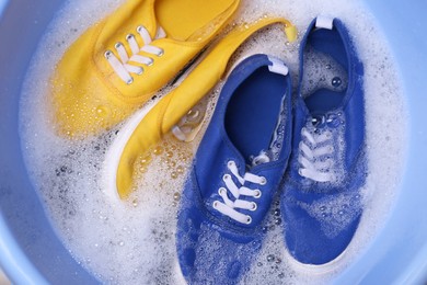 Photo of Washing sport shoes in plastic basin, top view