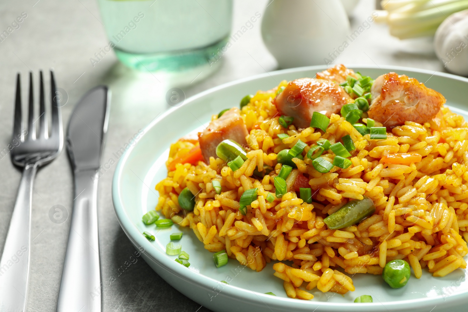 Photo of Delicious rice pilaf with vegetables and chicken on light grey table, closeup