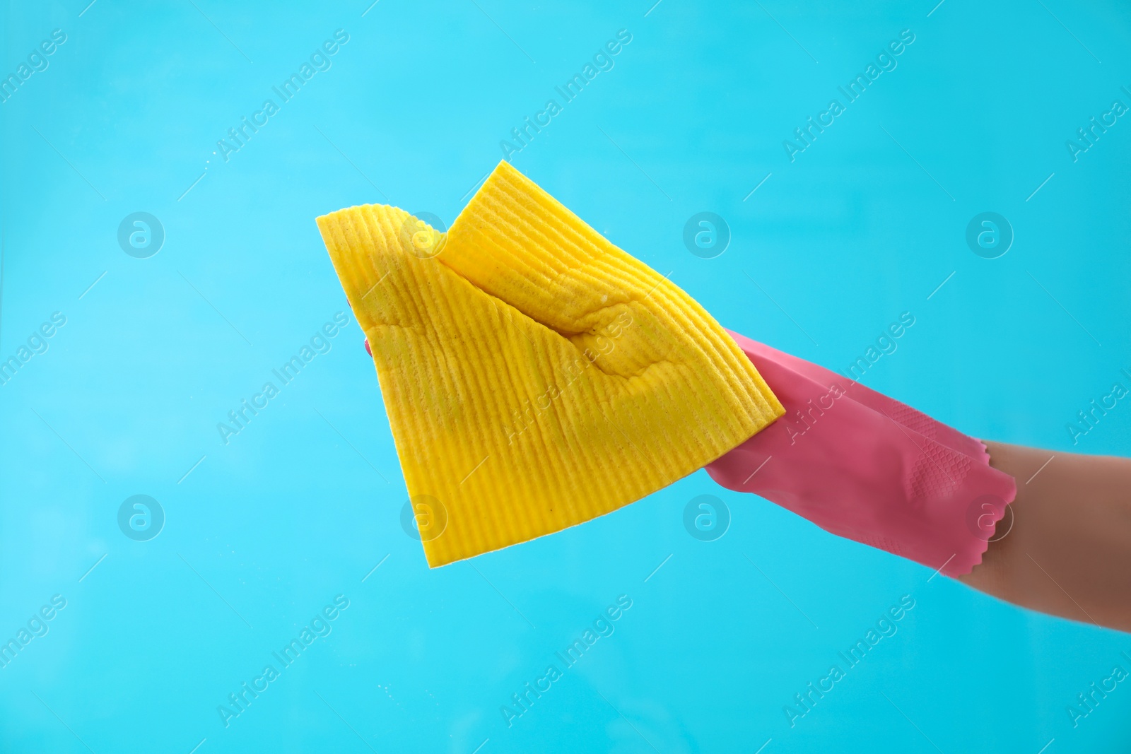 Photo of Woman cleaning glass with rag against color background