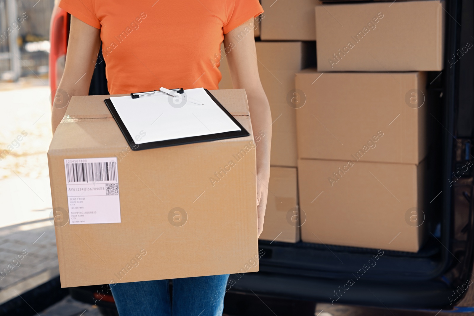 Photo of Courier holding package and clipboard near delivery truck outdoors, closeup