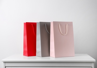 Photo of Paper shopping bags on white table against light background