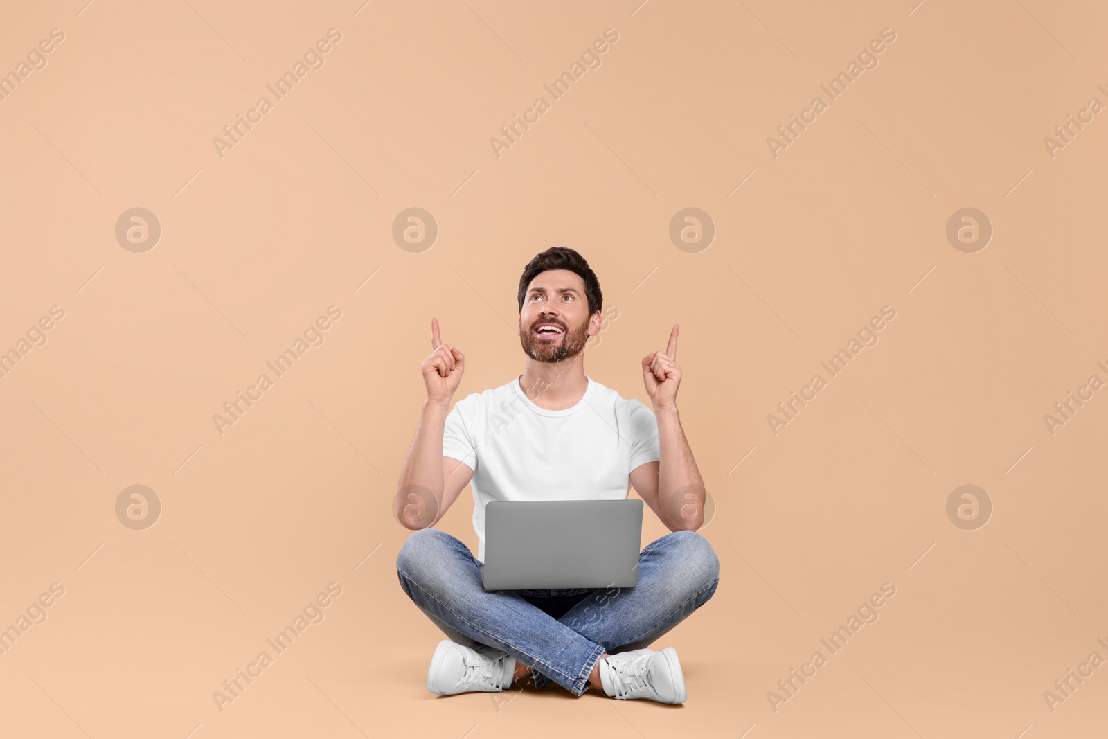 Photo of Happy man with laptop on beige background