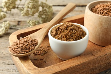 Photo of Caraway (Persian cumin) powder and dry seeds on wooden table, closeup