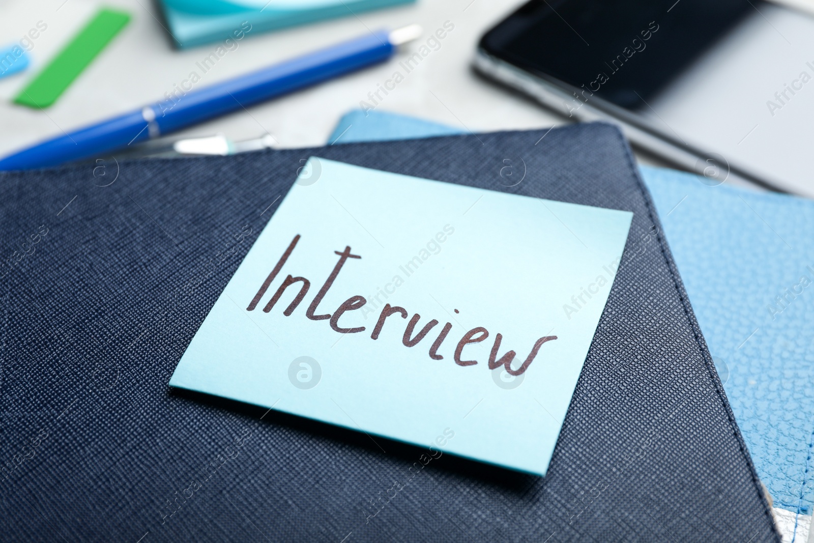 Photo of Reminder note about job interview and stationery on table, closeup