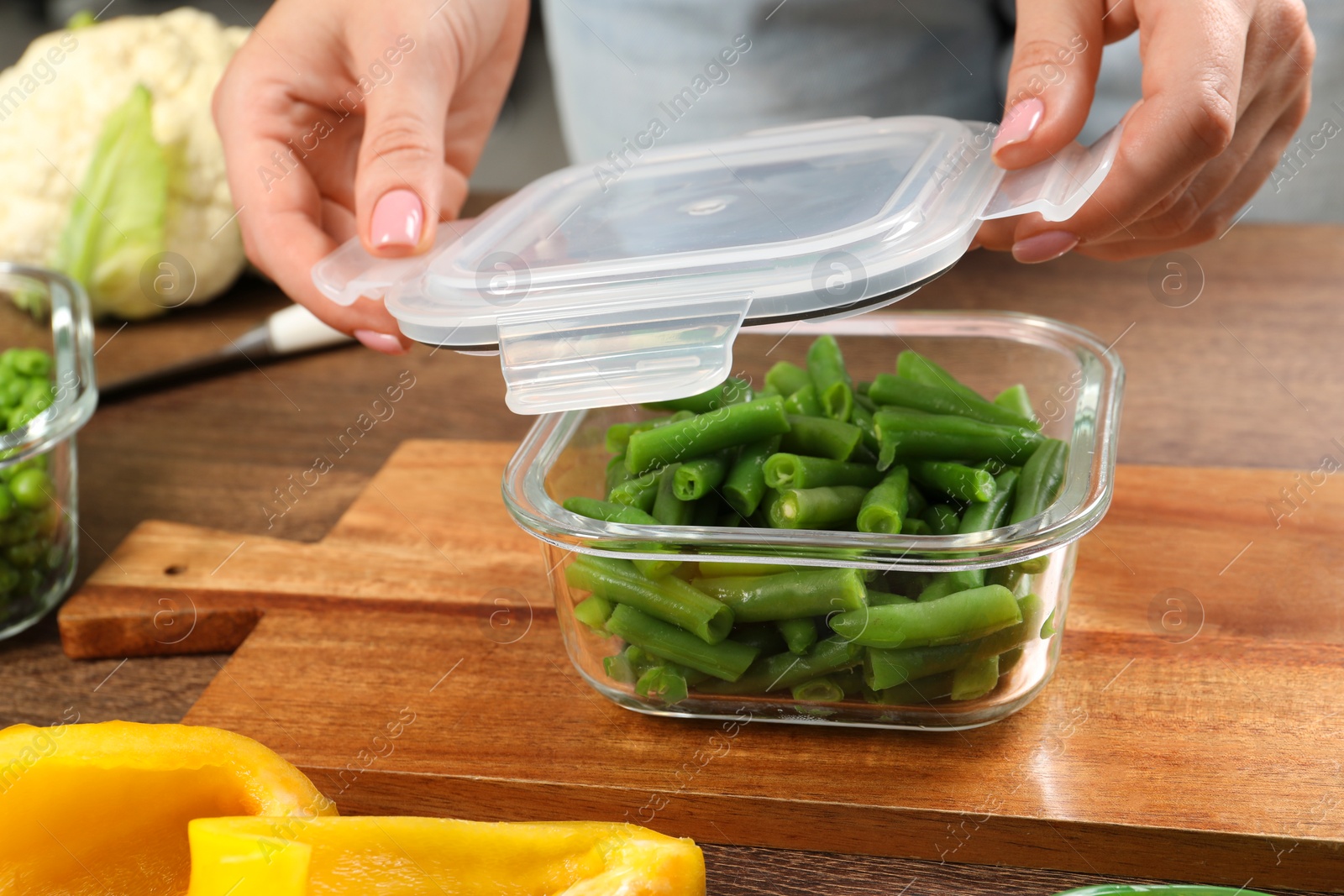 Photo of Woman closing container with lid at table, closeup. Food storage