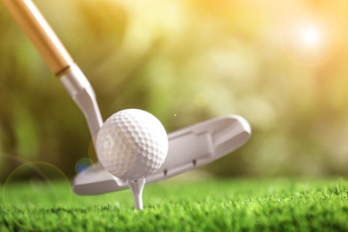Image of Hitting golf ball with club in park on sunny day. Space for design