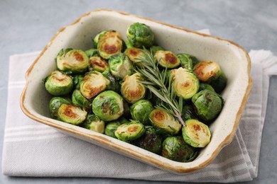 Photo of Delicious roasted Brussels sprouts and rosemary in baking dish on grey table