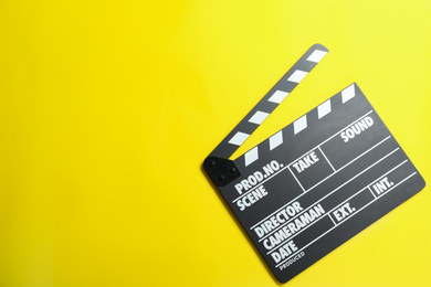 Photo of Clapper board on yellow background, top view with space for text. Cinema production