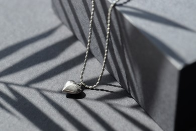 Photo of Metal chain with pendant on black table, closeup. Luxury jewelry