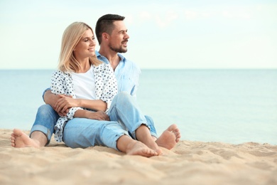 Happy romantic couple spending time together on beach, space for text