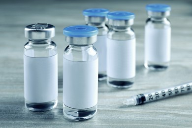 Image of Medication in glass vials and syringe on white wooden table
