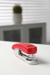 Photo of One stapler on white table indoors. Office stationery