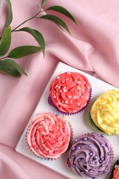 Photo of Delicious cupcake with bright cream on pink fabric, top view