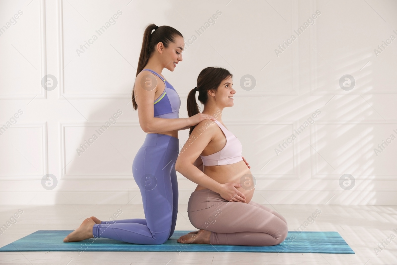 Photo of Trainer working with pregnant woman in gym. Preparation for child birth