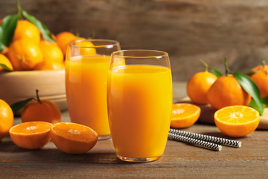 Photo of Glasses of fresh tangerine juice and fruits on wooden table