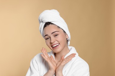 Photo of Portrait of attractive young woman in bathrobe with towel on beige background. Spa treatment