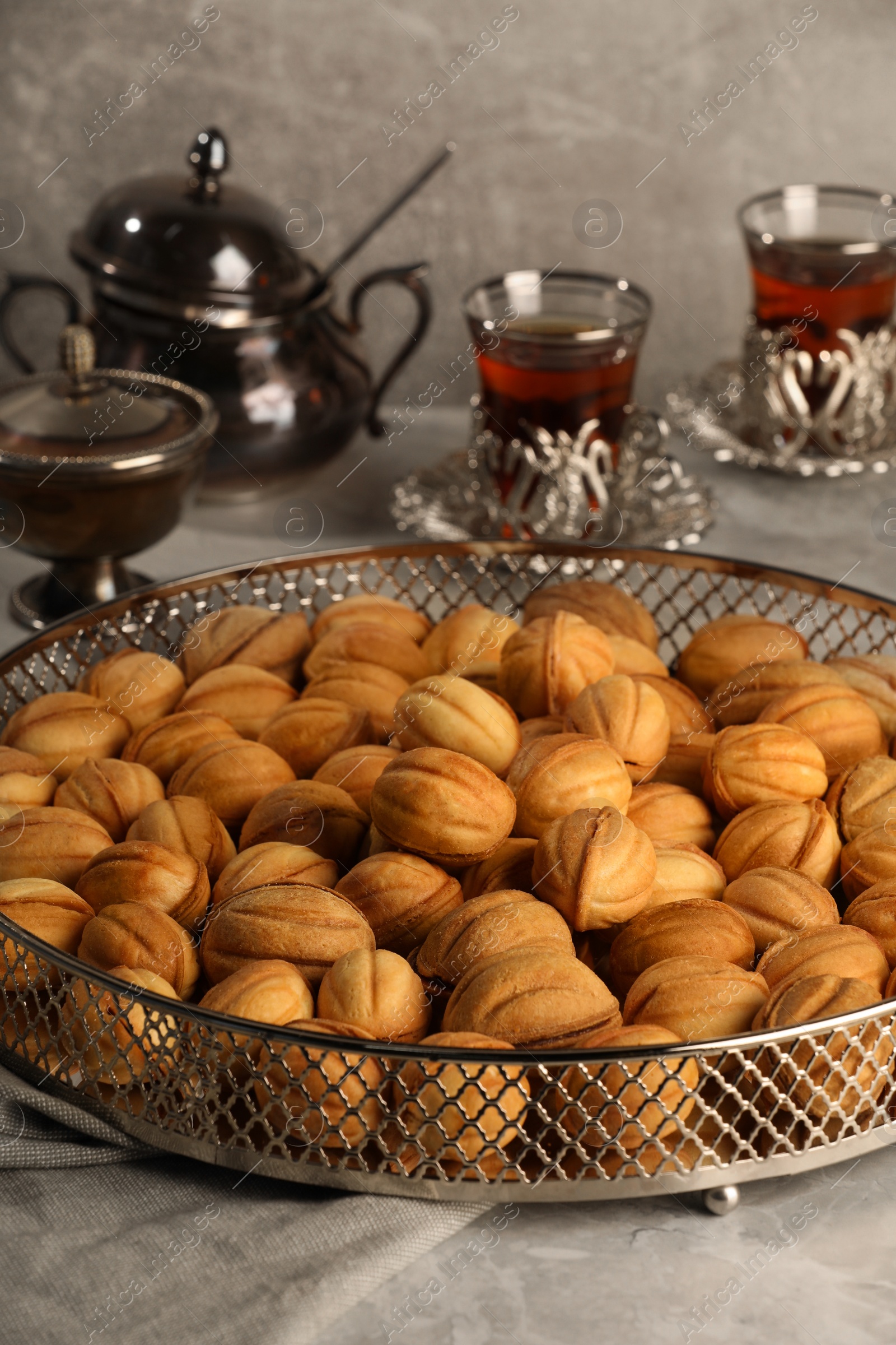 Photo of Delicious walnut shaped cookies and tea on grey table. Tasty pastry carrying nostalgic home atmosphere