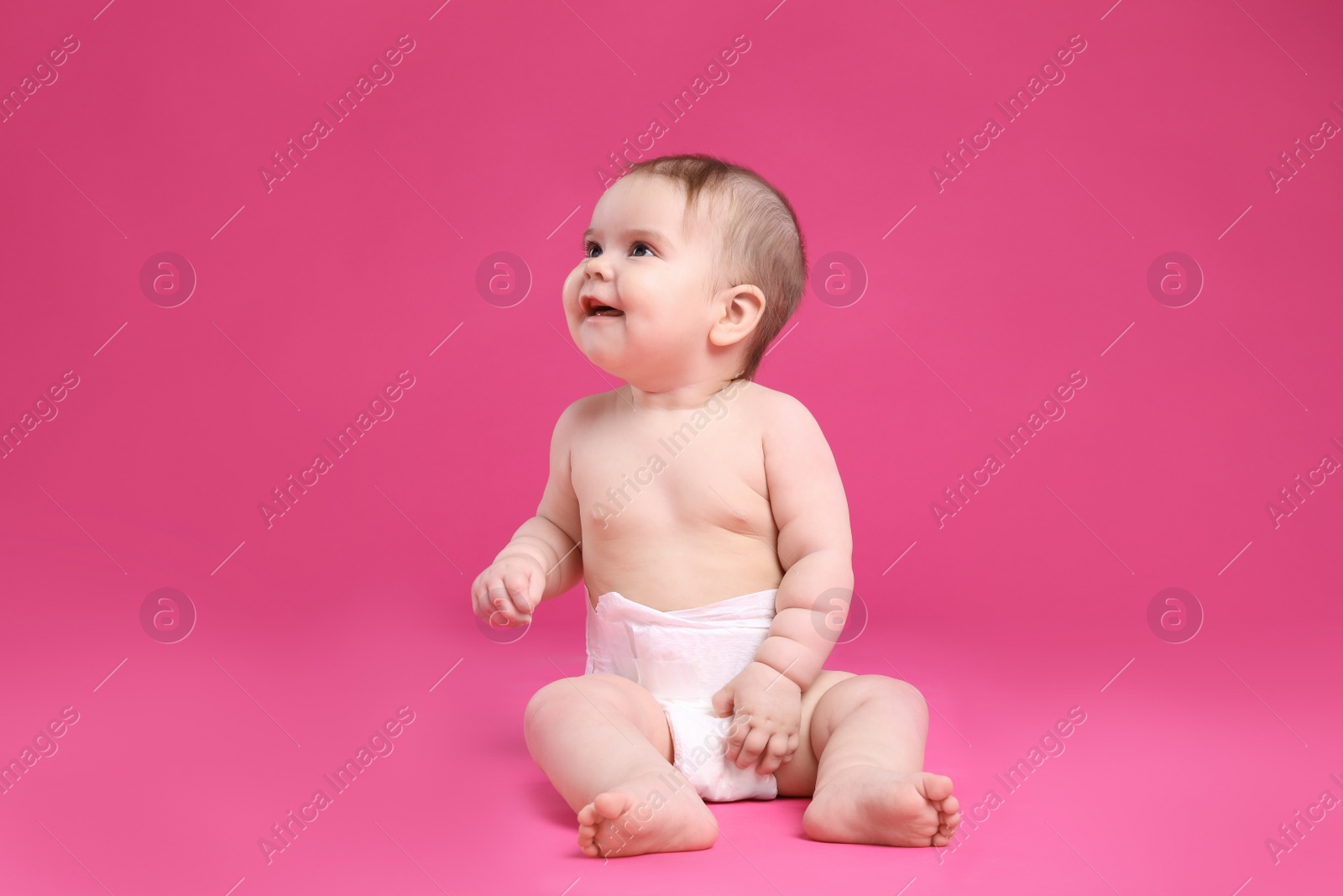 Photo of Cute little baby in diaper sitting on pink background