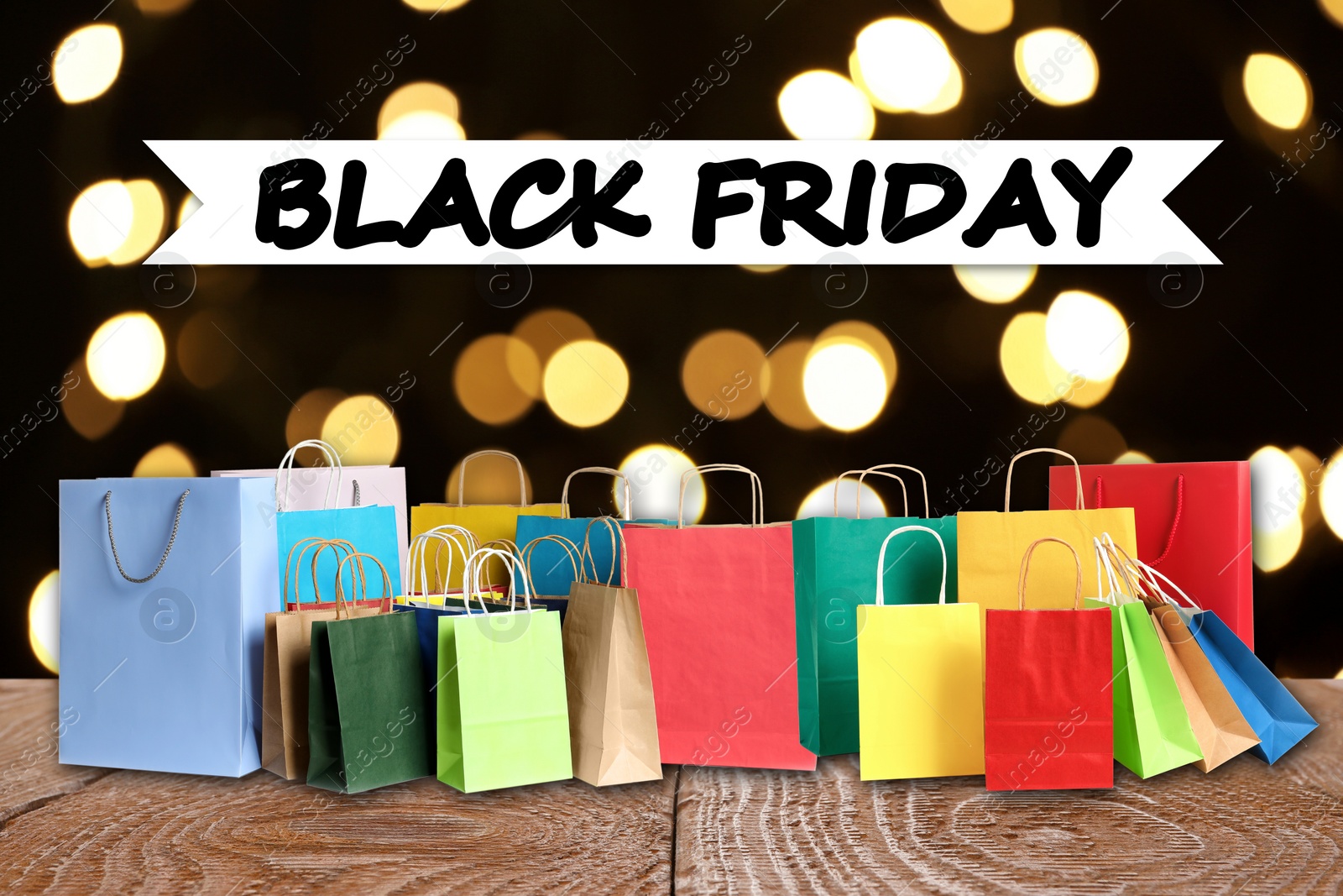 Image of Black Friday. Many shopping bags on wooden table against blurred lights 