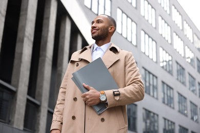 Photo of Happy man with folders outdoors, low angle view. Lawyer, businessman, accountant or manager