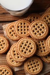 Photo of Tasty sandwich cookies with cream and glass of milk on wooden table, flat lay